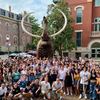 group of people waving in front of a mammoth statue